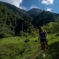 Hiker crossing Río Santo Domingo on Valle de las Cascadas trek