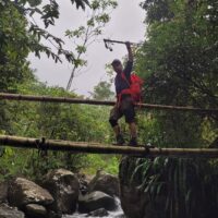 Hiker crossing river in Valle de las Cascadas, Antioquia