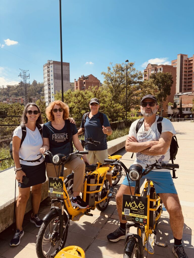Smiling travelers riding electric bikes with Comuna 13 in the background