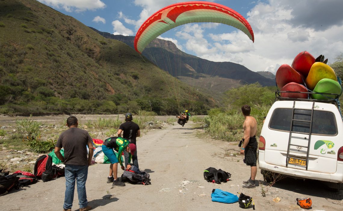 paragliders landing beside van loaded with kayaks